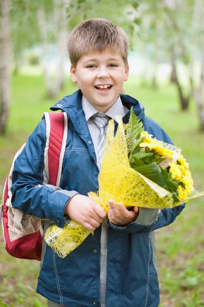 Schoolboy with a bouquet of yellow chrysanthemums in the park — Stock Photo, Image