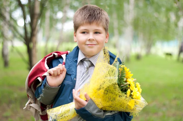 Skolpojke med en bukett av gula krysantemum i parken — Stockfoto