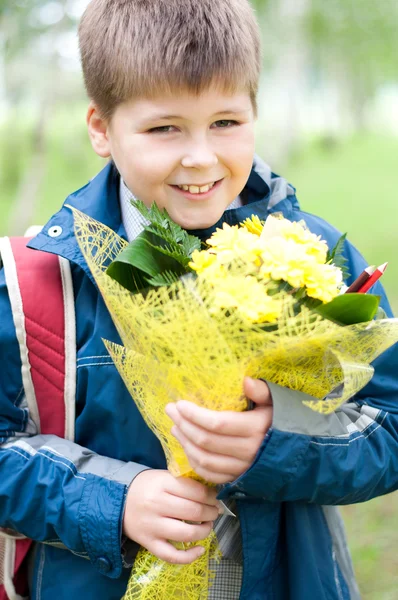 Schoolboy with a bouquet of yellow chrysanthemums in the park — Stock Photo, Image