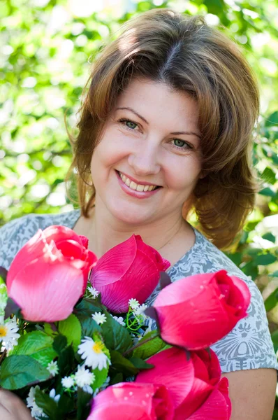 Femme avec un bouquet de fleurs artificielles dans le parc d'été — Photo