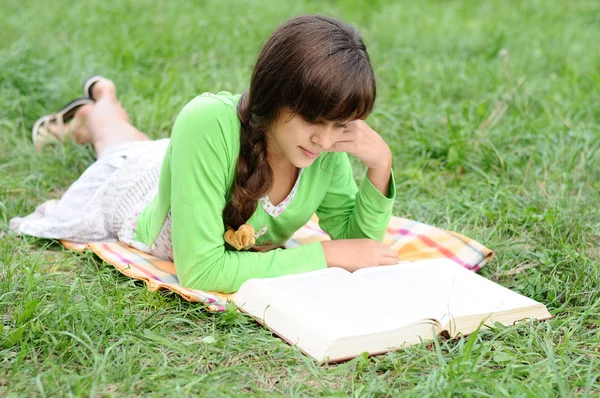 Κορίτσι, διαβάζοντας ένα βιβλίο, που βρίσκεται στο γρασίδι — Φωτογραφία Αρχείου