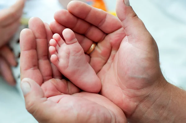 Jambe du nouveau-né entre les mains du père — Photo