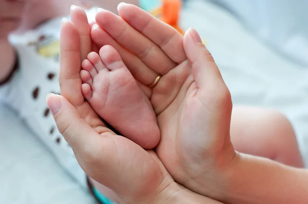 Bein des Neugeborenen in den Händen der Mutter Stockfoto