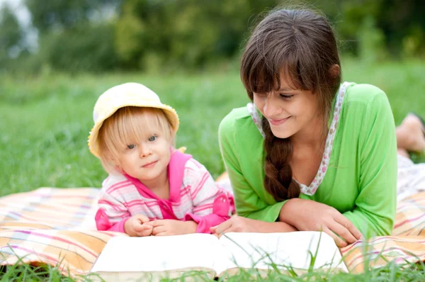 Two sisters reading a book outdoors — Stock Photo, Image