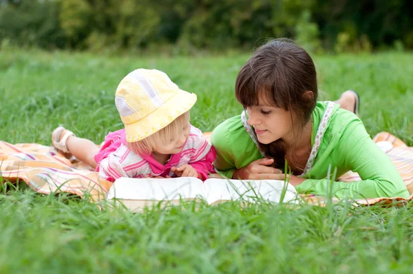 Two sisters reading a book outdoors — Stock Photo, Image