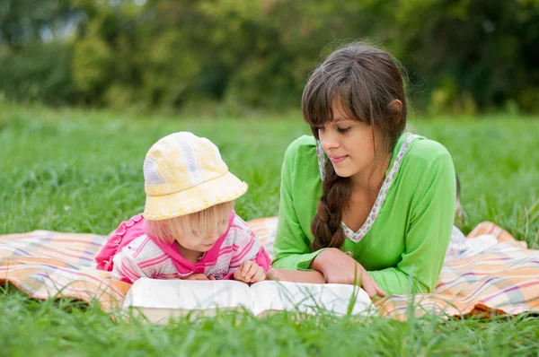 Two sisters reading a book outdoors — Stock Photo, Image