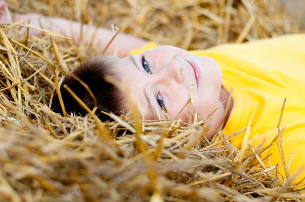 Kluk leží na slámě — Stock fotografie