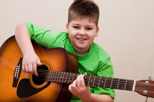 Chłopiec uczy się grać na gitarze — Zdjęcie stockowe