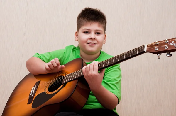 A boy learns to play the guitar — Stock Photo, Image