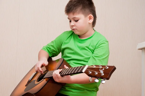 En pojke lär sig att spela gitarr — Stockfoto
