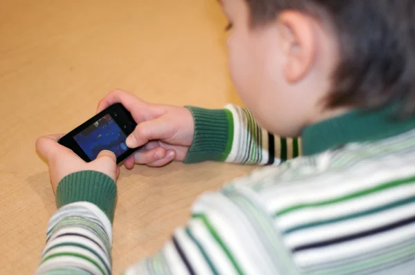 Мальчик играет на мобильном телефоне — стоковое фото