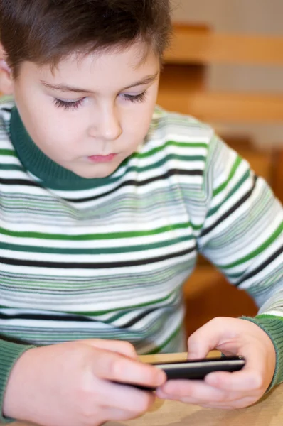 Pojke spelar på en mobiltelefon — Stockfoto