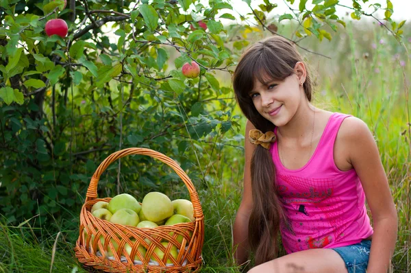 Tiener meisje met een mand met appelen — Stockfoto