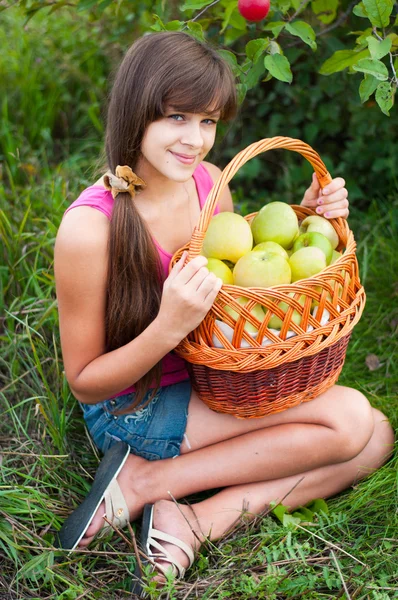 Tiener meisje met een mand met appelen — Stockfoto