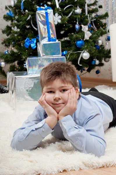 クリスマスの木の近くのギフトを持つ少年 — ストック写真