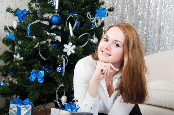 Μια νεαρή γυναίκα με δώρα κοντά ένα χριστουγεννιάτικο δέντρο — Φωτογραφία Αρχείου