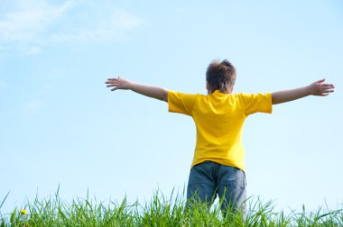 Yeşil çimenlerin üzerinde bir çocuk duruyor