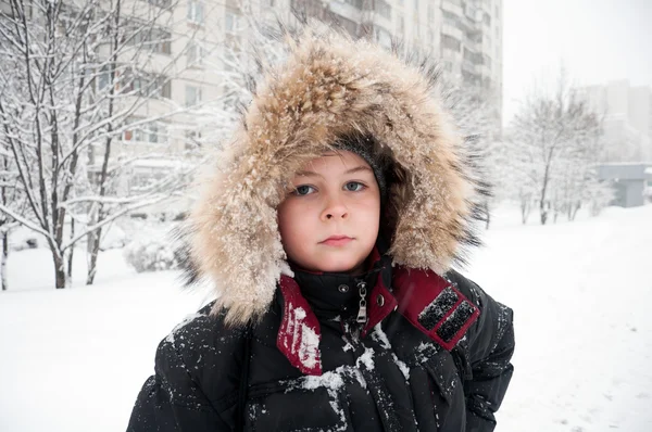 Porträtt av en pojke i vinterkläder under snöfall — Stockfoto