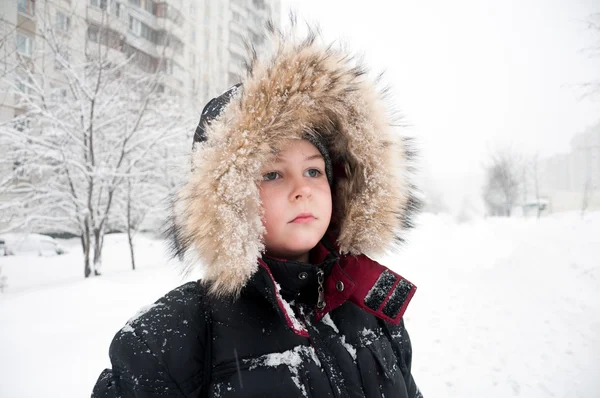 Ritratto di un ragazzo in abiti invernali durante la nevicata — Foto Stock