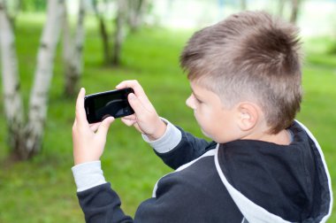 bir çocuk bir parkta bir cep telefonu üzerinde çalış.