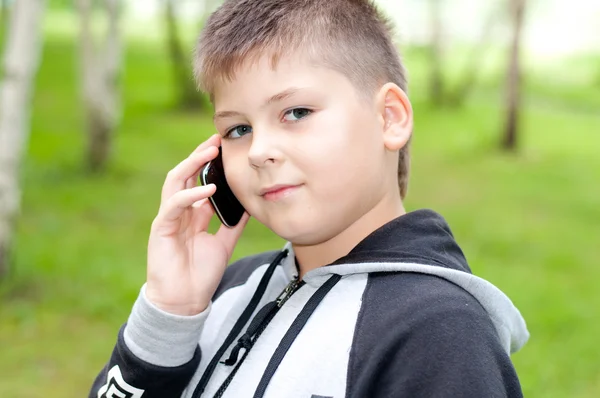 Boy talking on a cell phone in the park — Stock Photo, Image