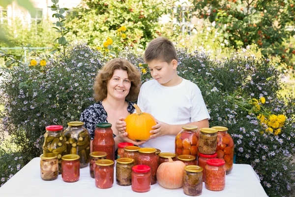 Mãe com seu filho e legumes enlatados em casa — Fotografia de Stock