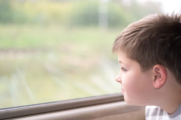 El chico mira en la ventana del tren — Foto de Stock