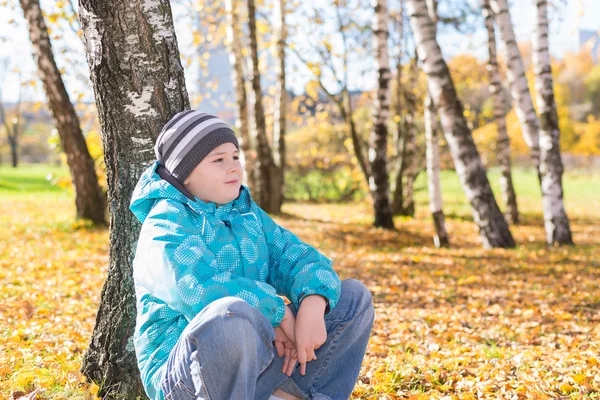 Грустный мальчик в осеннем парке — стоковое фото