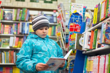 The boy chooses a book in the shop clipart