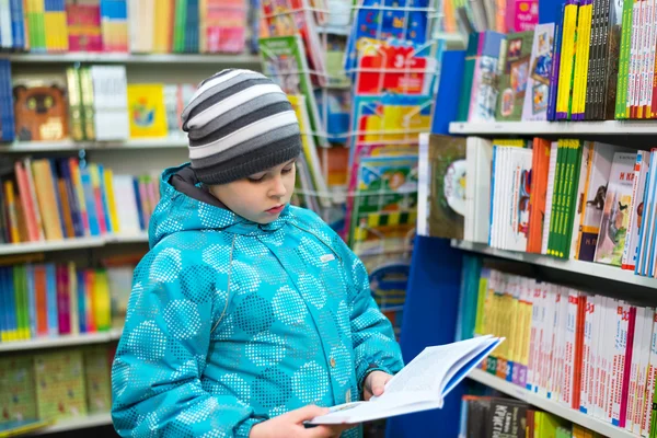 The boy chooses a book in the shop — Stock Photo, Image