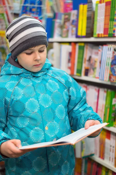 The boy chooses a book in the shop — Stock Photo, Image