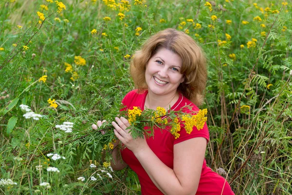 Middle-aged woman on a meadow with tansy — Stock Photo, Image