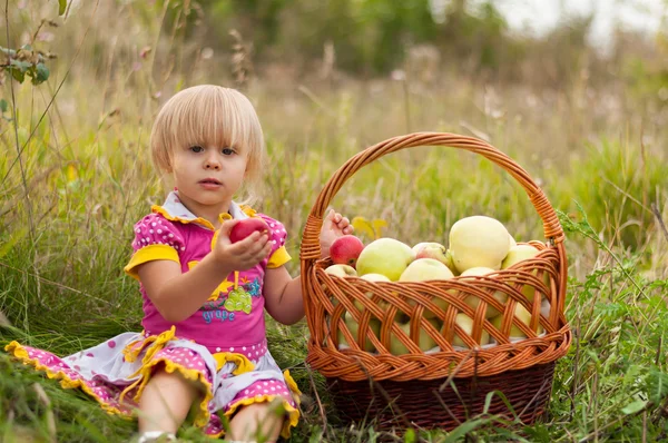 Niña con una cesta de manzanas frescas — Foto de Stock