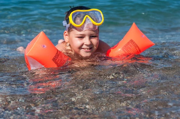 Мальчик учится плавать с рукавами — стоковое фото