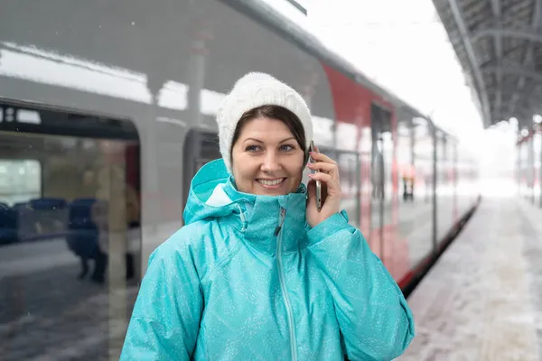 Woman talking on phone against background of train in winter in Moscow, Russia — Stock Photo, Image