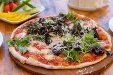 Jambonlu pizza ve tahta masada salata.