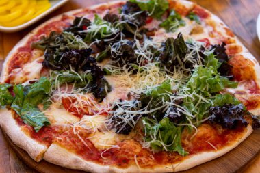 Jambonlu pizza ve tahta masada salata.