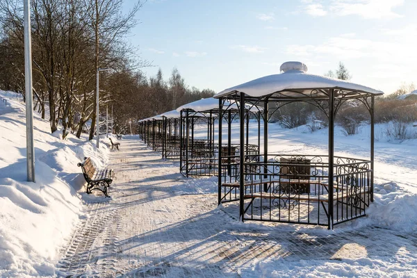 Fila de gazebos de metal em banco de lagoa congelada, Rússia Fotos De Bancos De Imagens