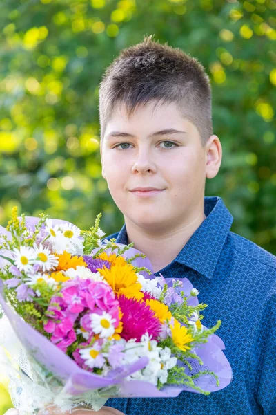 Tonårspojke med blombukett i naturen — Stockfoto