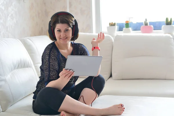 Mulher trabalhando em tablet e usando fones de ouvido — Fotografia de Stock