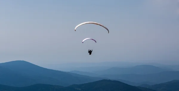 Parapente sobre a montanha contra o céu azul — Fotografia de Stock