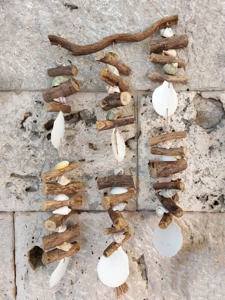古代の石壁に掛けられた木や貝殻で作られた伝統的なギリシャのお守り 風のチャイム — ストック写真