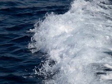 Mavi deniz suyunda beyaz köpüklü dalgalı gemi izleri.