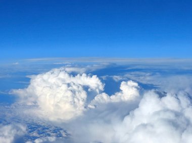 Bir uçak penceresinden güzel beyaz bulutlara ve açık mavi gökyüzüne bak.