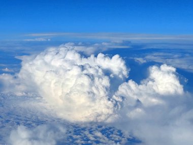 Bir uçak penceresinden güzel beyaz bulutlara ve açık mavi gökyüzüne bak.