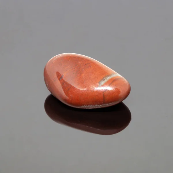 暗い背景に赤い碧玉の石をタンブリング — ストック写真