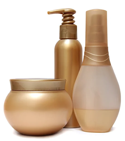 Três frascos de plástico dourado e garrafas isoladas sobre fundo branco . — Fotografia de Stock