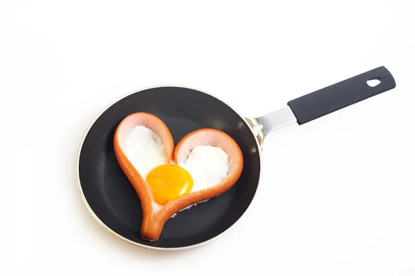 kalp üzerinde beyaz bir tavada kızarmış Yumurtalı Sosis şeklinde