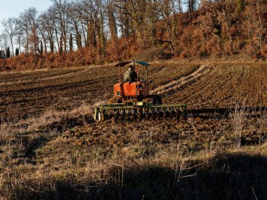 Tarım, traktör, ekili ekiciyle toprağı hazırlıyor. Tarım arazilerindeki tarım çalışmalarının ilkbahar başlarında tohumlama faaliyetlerinin bir parçası olarak..