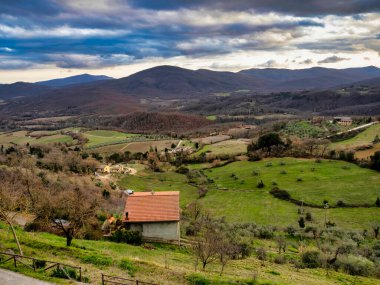 Tanınmış Toskana manzarası tahıl tarlaları, selvi ağaçları ve gün batımında tepelerde evler. Tuscany, İtalya ve Avrupa 'da kıvrımlı yolu olan yaz kırsal arazisi